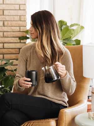 Žena v béžovém svetru s baristickou skleněnou konvičkou na espresso, moderní design, Nejnovější zprávy, vše o kávě.