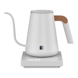 Bílá elektrická rychlovarná konvice s úzkým výtokem a dřevěným detailem na rukojeti, pro baristu a příslušenství k filtrované kávě, vše o kávě.